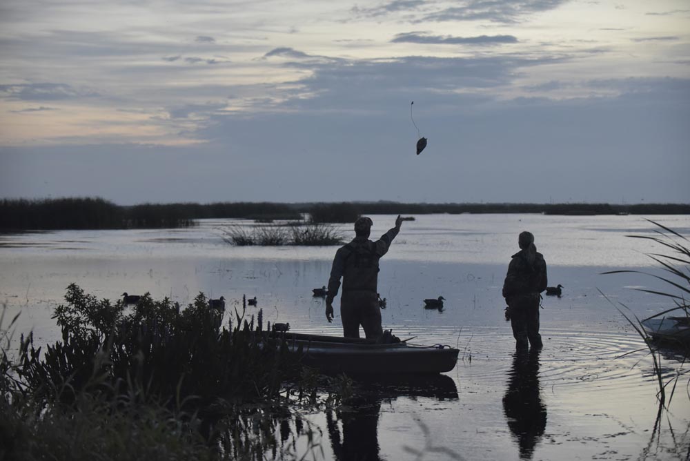 duck-hunt-putting-out-decoys_48947260107_o a group of people in a boat in a lake